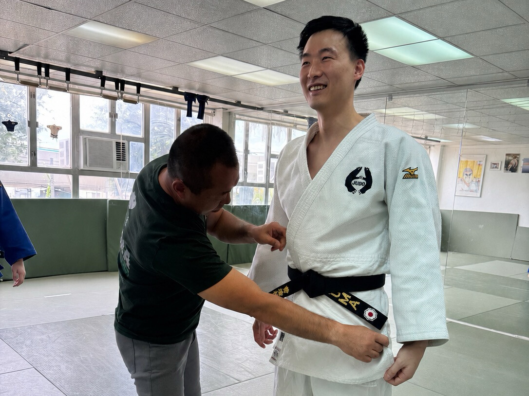 Kuma adjusting a student black belt at the dojo