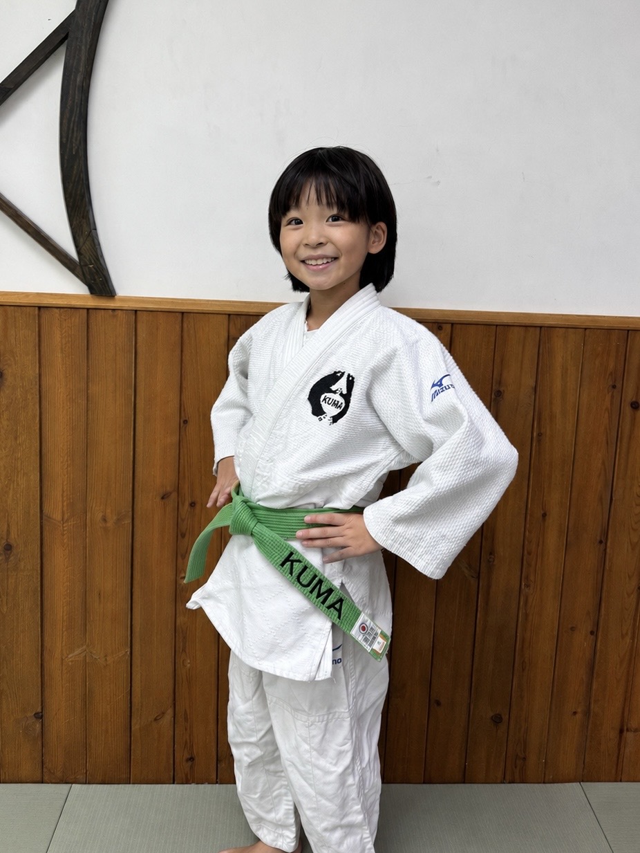 Kuma Dojo child judoka smiling after earning a green belt